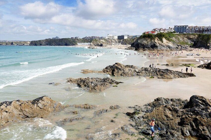 A rocky beach with waves, people, and buildings in the background. 4