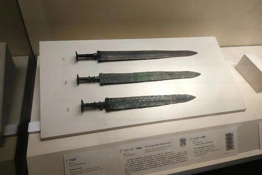 Tres espadas antiguas exhibidas sobre un soporte blanco, cada una con un diseño de empuñadura distinto. 4