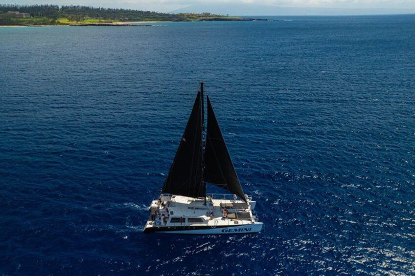 A sailboat named GEMINI on a large body of water with a distant shoreline. 5