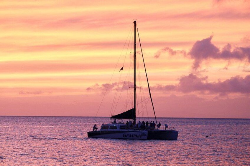 A sailboat with people on board, sailing on the water during sunset. 1
