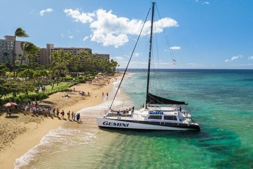 A beach with a sailboat named GEMIN, palm trees, and a hotel in the background. 2