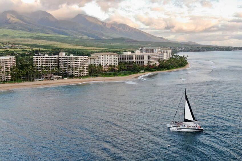 A coastal area with a sailboat on the water, a beach, and a row of buildings. 3