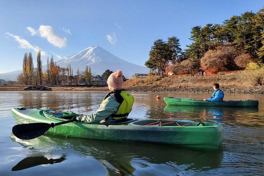 Two people kayaking on a calm river with a mountain in the background. 2