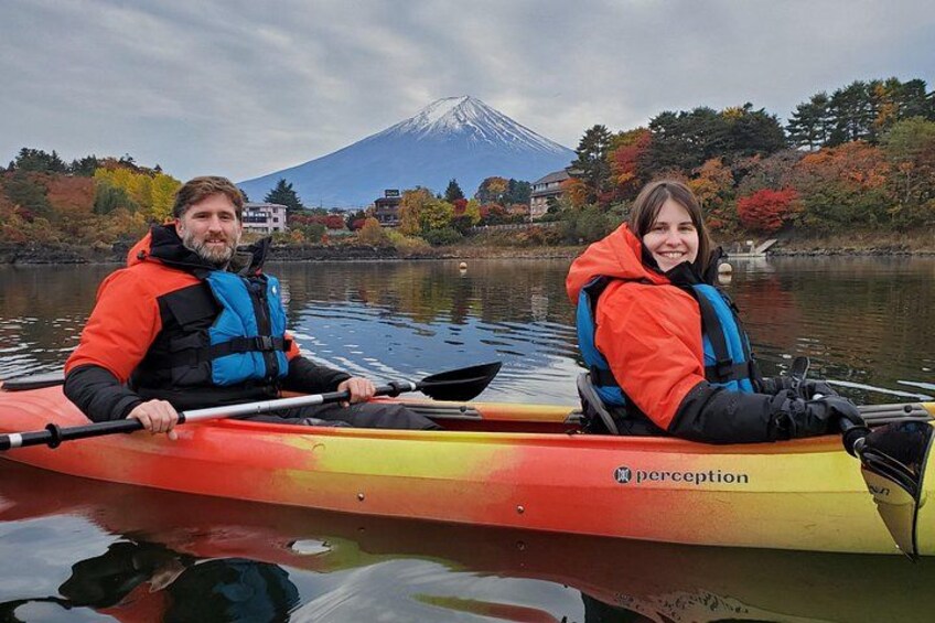 Two people kayaking on a calm lake with a mountain in the background. 2