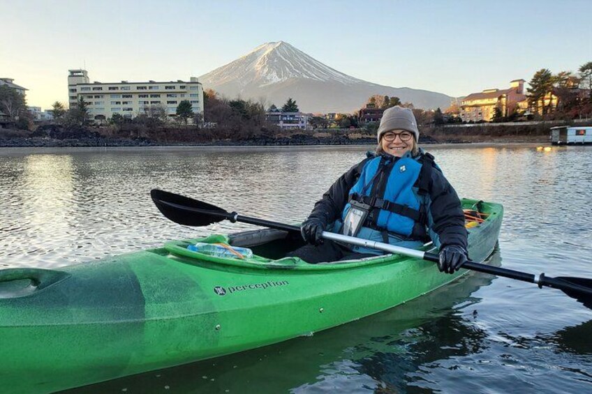 Una persona en kayak verde sobre aguas tranquilas, con una montaña al fondo. 3