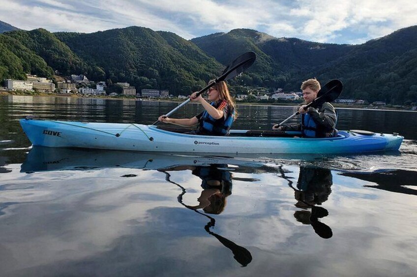 Two people kayaking on a calm lake with mountains in the background. 4