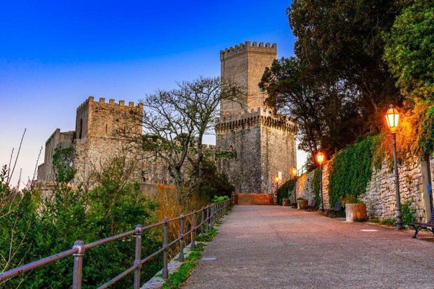 A stone castle with a tower, a paved pathway, and a railing. 5