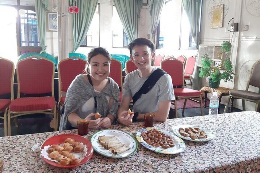 Two people sitting at a table with plates of food and drinks. 2