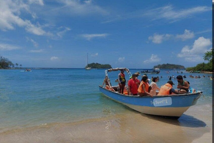 A boat with people on a beach, clear water, and distant islands. 3