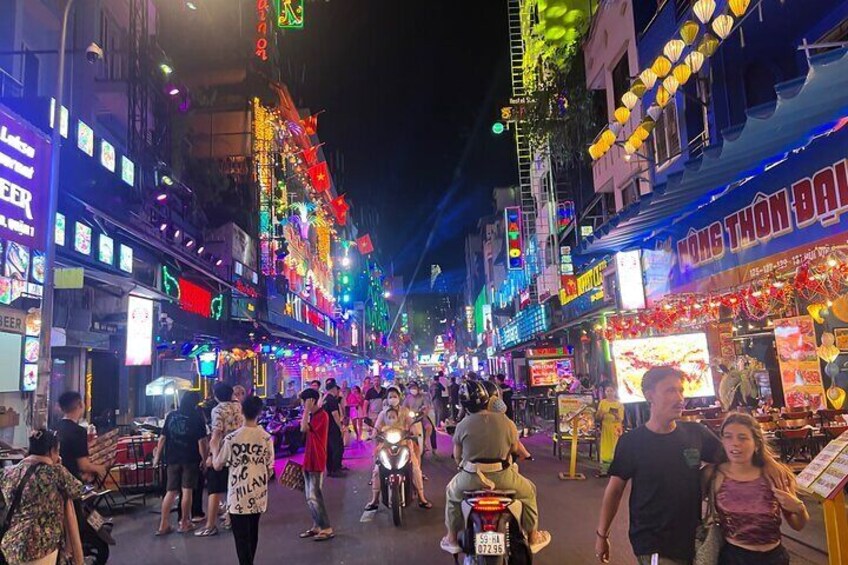 A bustling street at night with neon signs and illuminated storefronts. 2