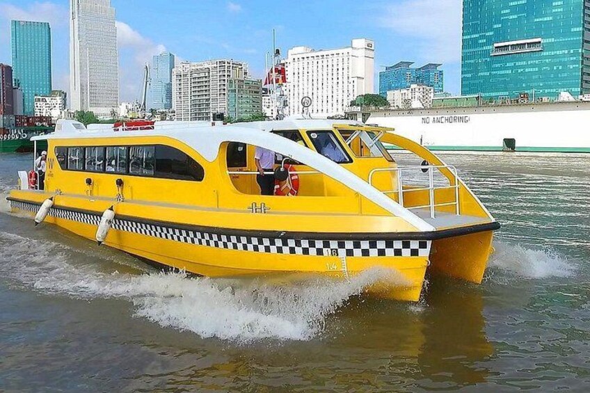 A yellow speedboat with a checkered pattern on its side, moving through a body of water with a cityscape in the background. 5