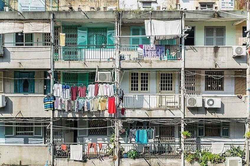 A multi-story residential building with balconies, air conditioning units, and laundry hanging outside. 3