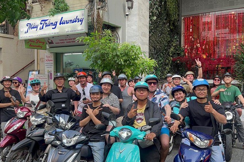 A group of people on motorcycles in front of a laundry shop. 1