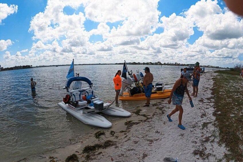 Ein Strand mit Menschen, einem Boot und einem Sandufer. 2