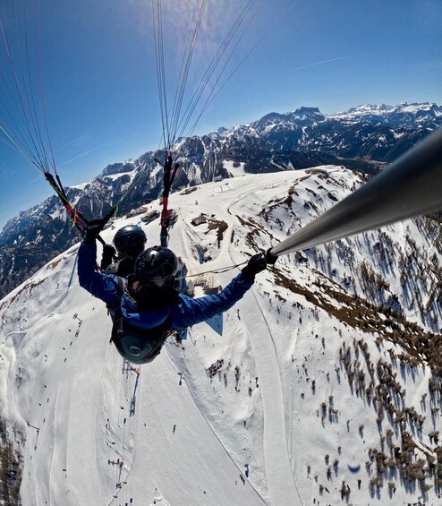 A person paragliding over a snowy mountain landscape with clear skies. 2
