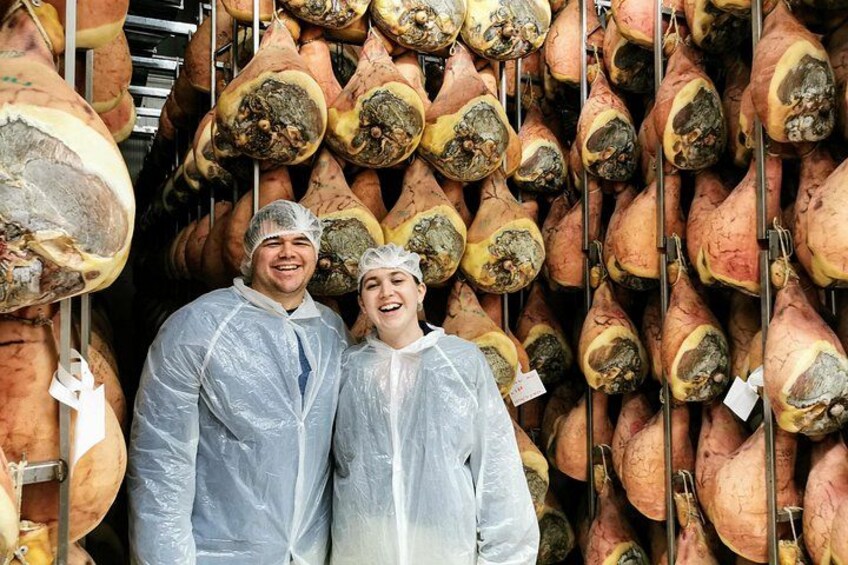 Twee personen in beschermende kleding staan in een opslagruimte met grote, hangende zoete aardappelen. 3