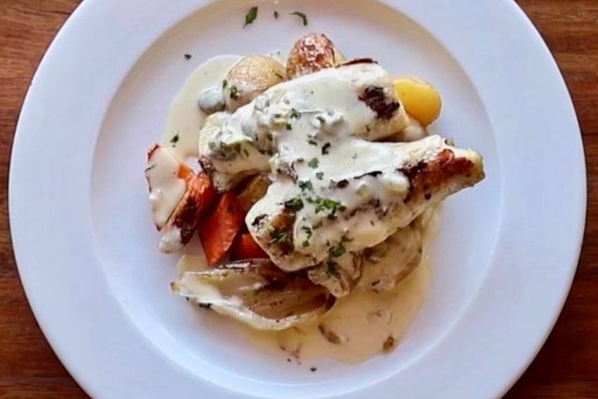A plate of food with a white sauce, potatoes, and a piece of meat. 2