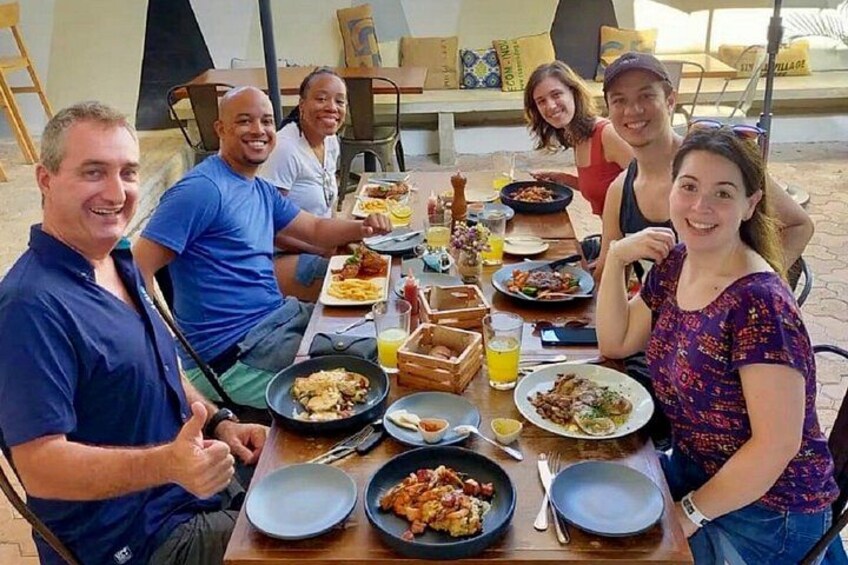 A group of people sitting at an outdoor table with various dishes and drinks. 4