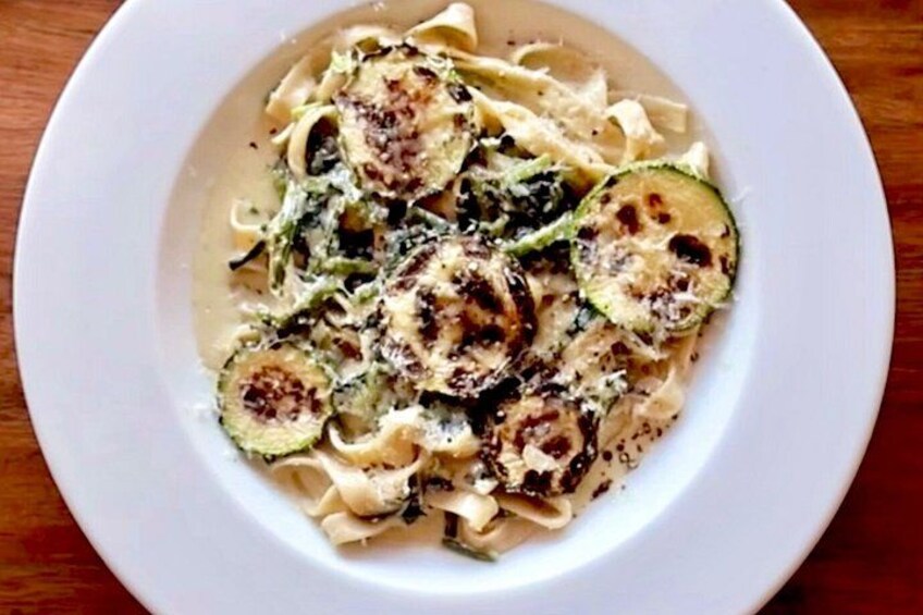 A plate of pasta with zucchini slices and grated cheese. 3