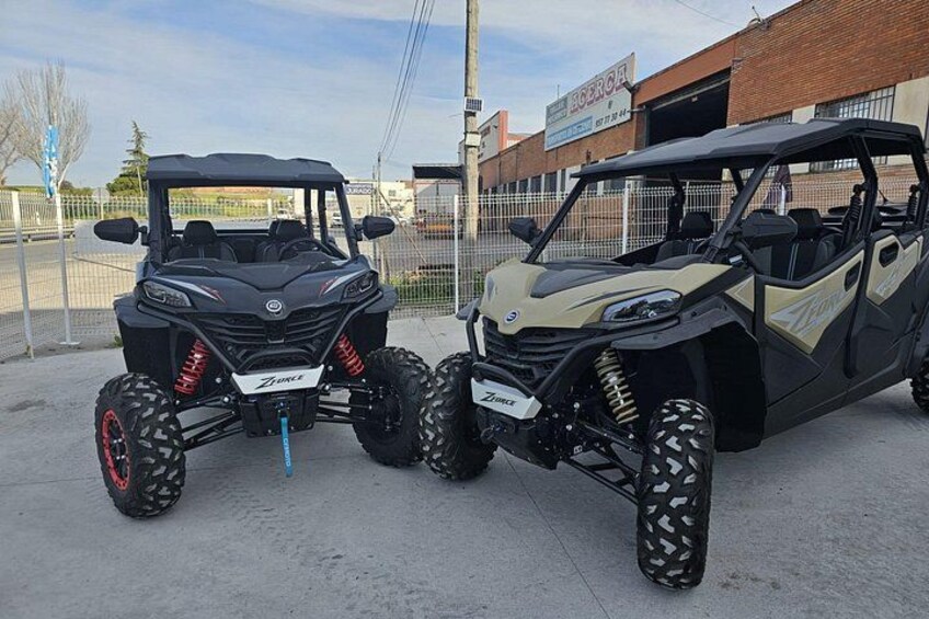 Deux véhicules tout-terrain sont stationnés sur un parking, avec un bâtiment en arrière-plan. 5