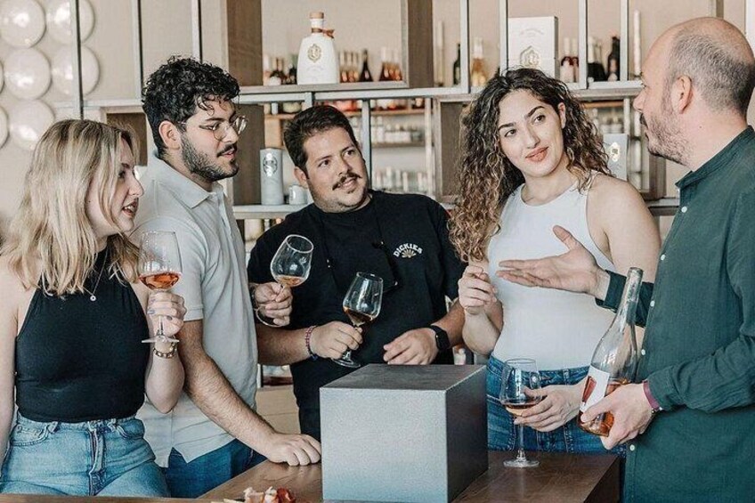 A group of people at a bar with wine glasses, a bottle of wine, and a bar counter. 4