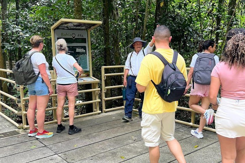 Un grupo de personas frente a un quiosco de madera informativo en una zona boscosa. 2