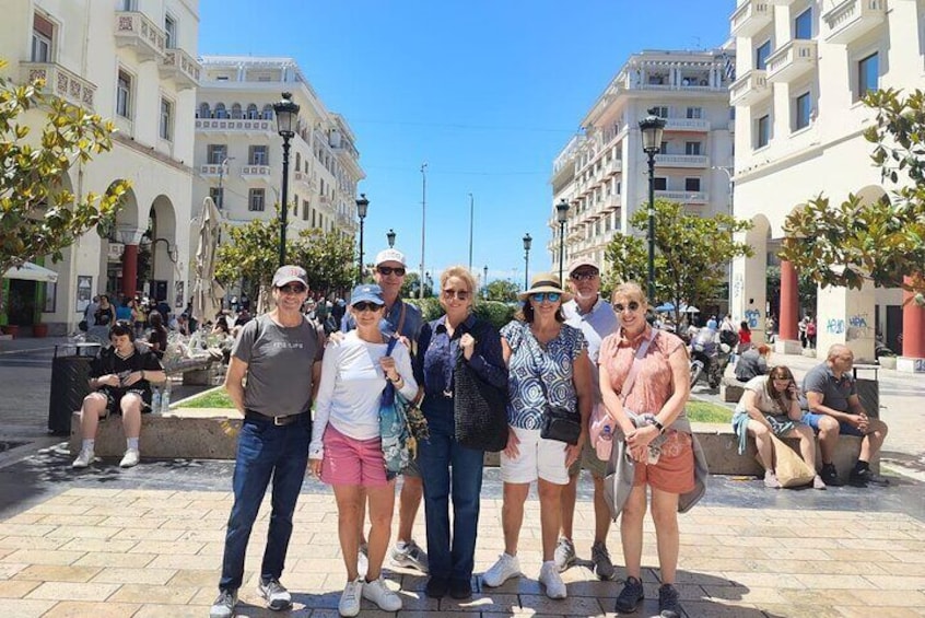 A group of people standing in a public square with buildings in the background. 3