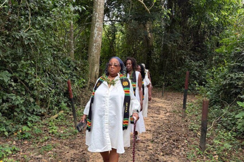Un grupo de personas vestidas con atuendos tradicionales caminando por un bosque. 4