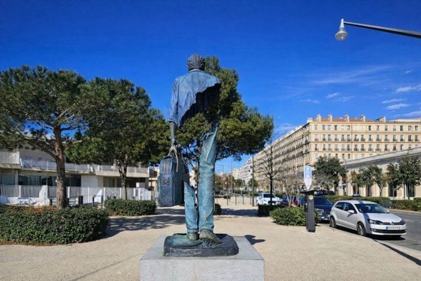 A statue of a man with a book, a tree, and a building in the background. 3