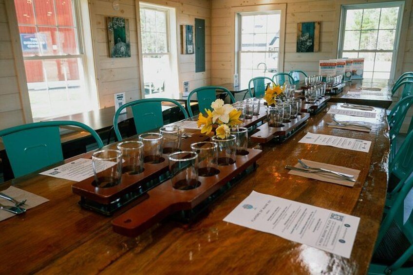 A wooden table set for a tasting event with glasses and a menu. 2