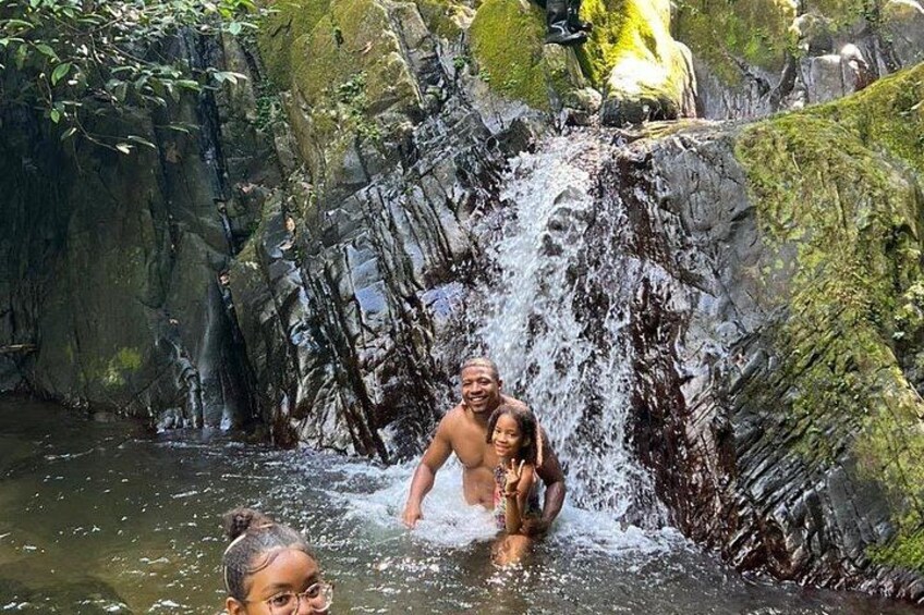 A waterfall in a rocky, moss-covered environment with people enjoying the water. 4