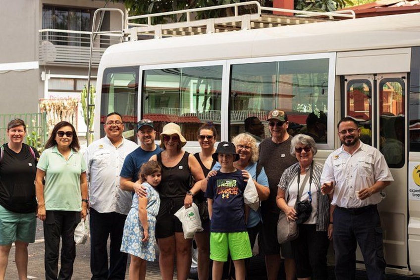 Eine Gruppe von Personen steht vor einem Bus im tropischen Design. 5