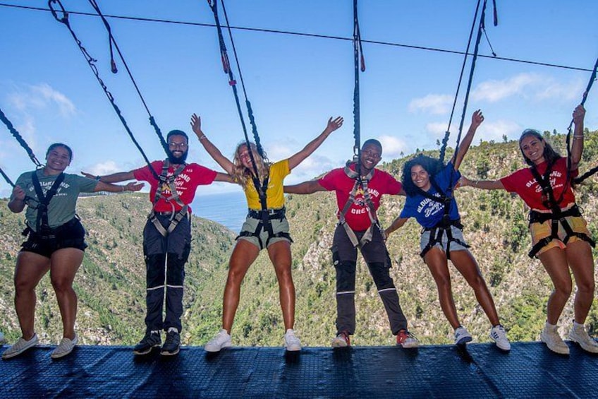 Eine Gruppe von Personen auf einer Zipline vor einer gebirgigen Landschaft. 4