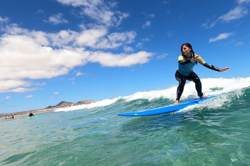 Une personne faisant de la planche à voile sur une vague, avec un ciel dégagé et des montagnes à l'horizon. 2