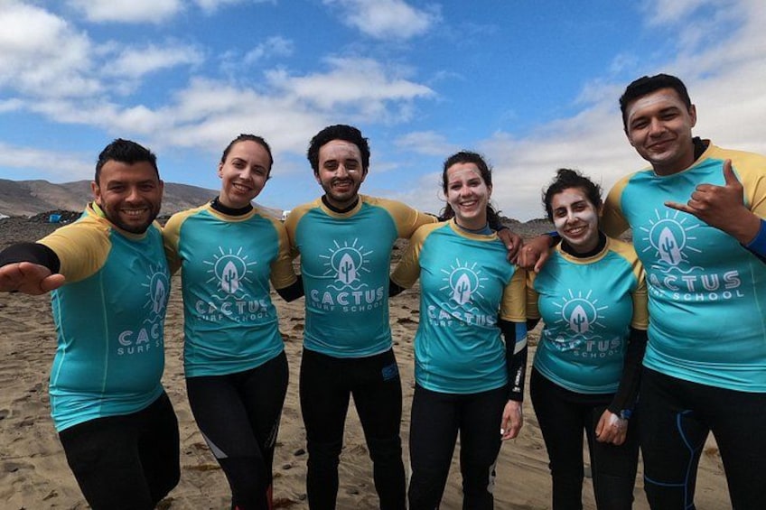 Un groupe de personnes, portant des t-shirts assortis avec un logo et un texte, se tient sur un terrain sablonneux sous un ciel dégagé. 1