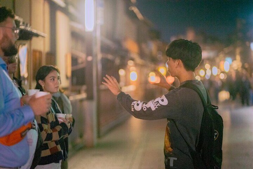 A person with a backpack standing on a street at night. 4