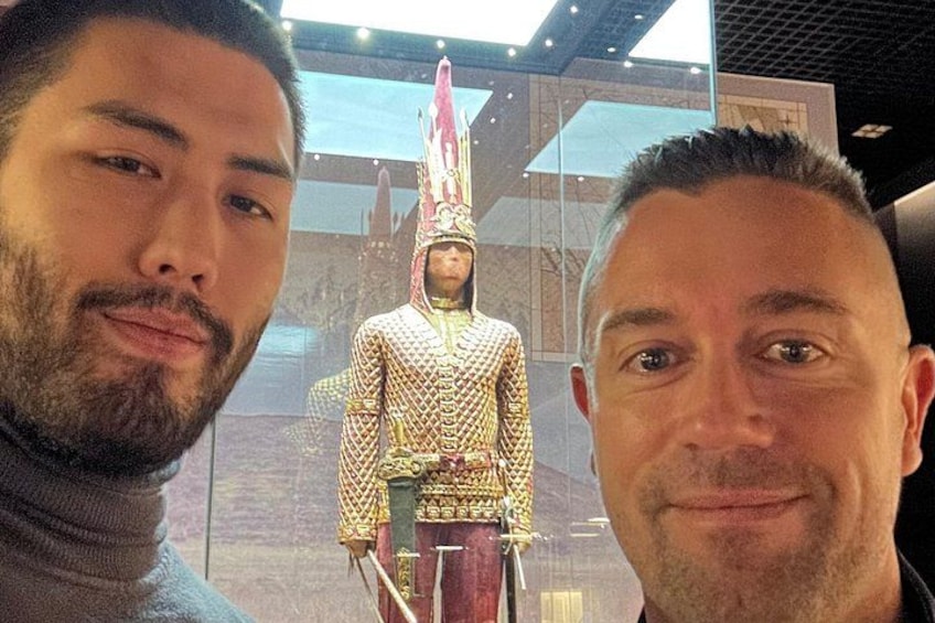 Two people in front of a museum exhibit featuring a historical figure in ornate armor. 2