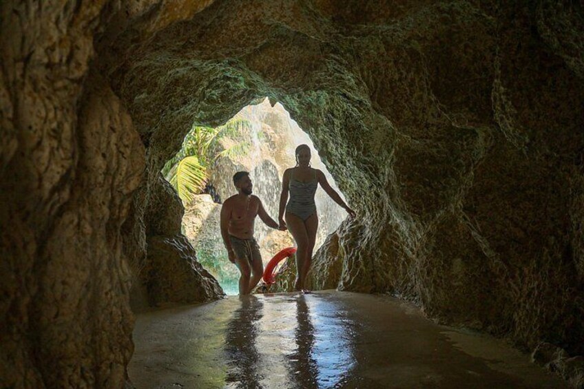 A cave with a water channel and a person holding a red object. 4