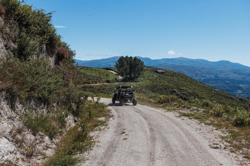 A jeep on a gravel road with mountains in the background. 3