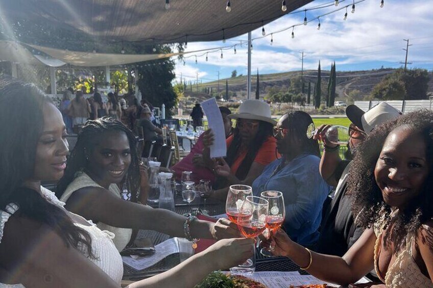 Des personnes trinquent avec des verres de vin lors d’un événement en plein air. 3