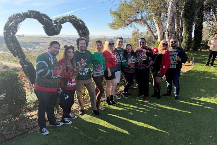 Un grupo de personas sobre una zona cubierta de césped, con una decoración en forma de corazón hecha de ramas. 2