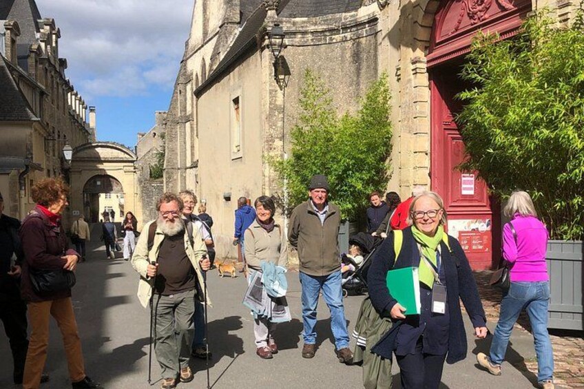 A group of people walking on a street with historic buildings and a red door. 2