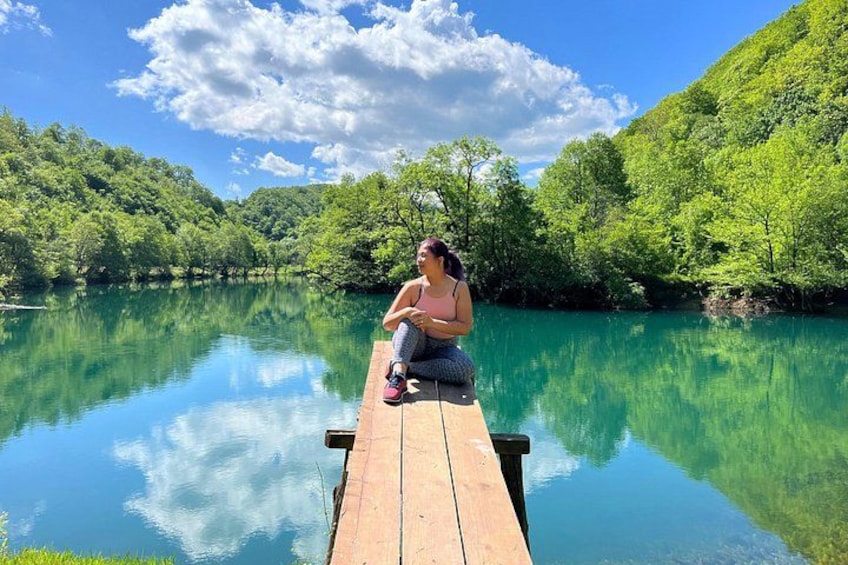 A wooden dock extending into a calm, turquoise lake surrounded by lush green hills. 5