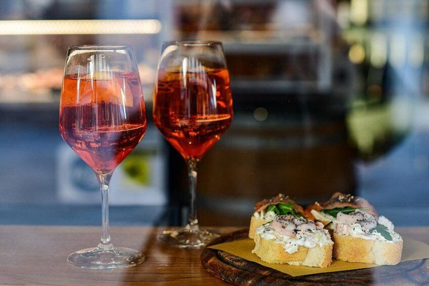 Two wine glasses with red liquid, a wooden table, and a plate with food. 1