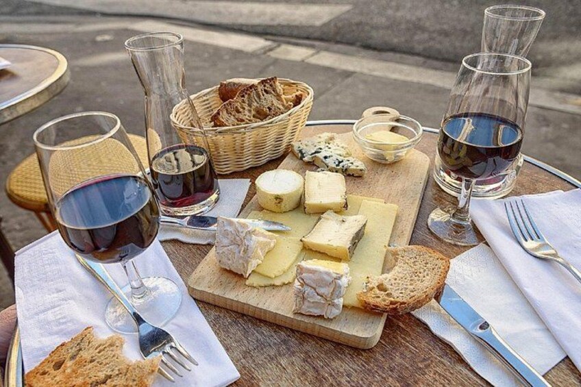 A cheese board with various cheeses, bread, and wine glasses on a table. 3