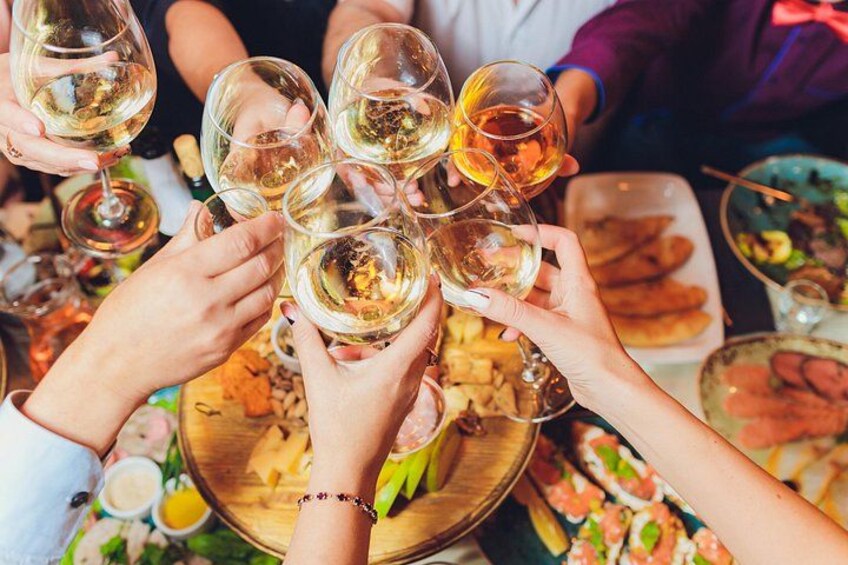 A group of people toasting with wine glasses at a dinner table with various dishes. 2