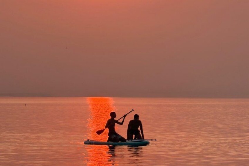 Two people on a paddleboard in calm water during sunset. 5