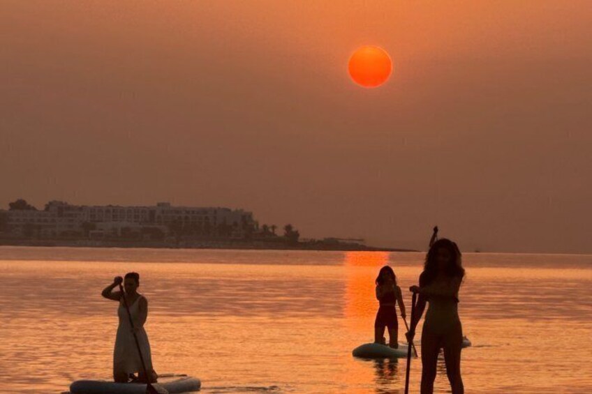 A sunset over water with paddleboards. 1