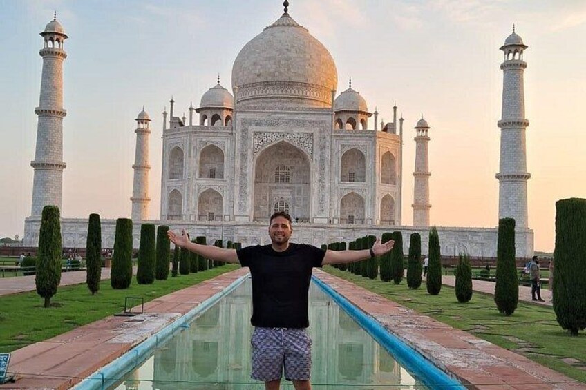 A person standing in front of the Taj Mahal with arms outstretched. 4