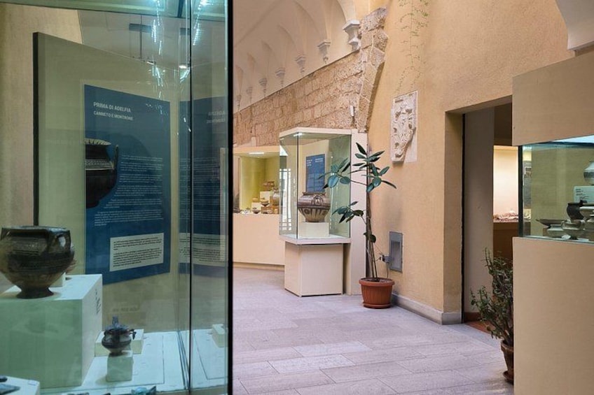 Et museum indeni med glasudstillingsmontre, informationsskilte og plantekasser. 4
